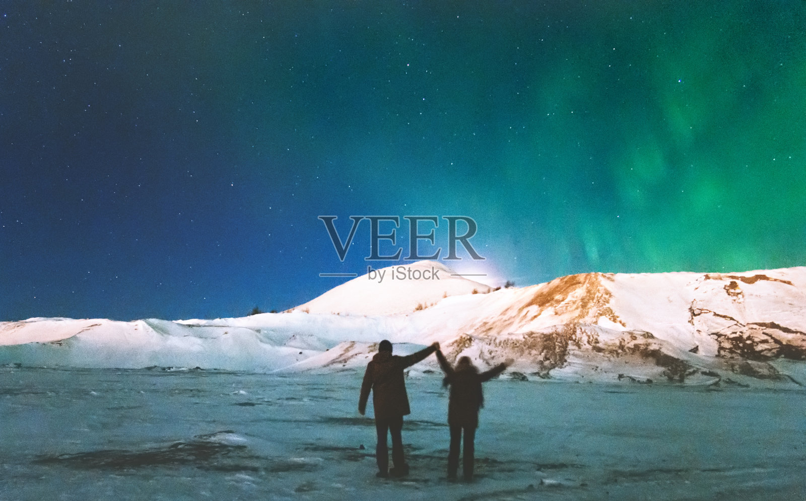 情侣旅行者享受在山上的北极光的观点举起手旅行的生活方式和关系男人和女人的概念假期进入野外的夜景照片摄影图片