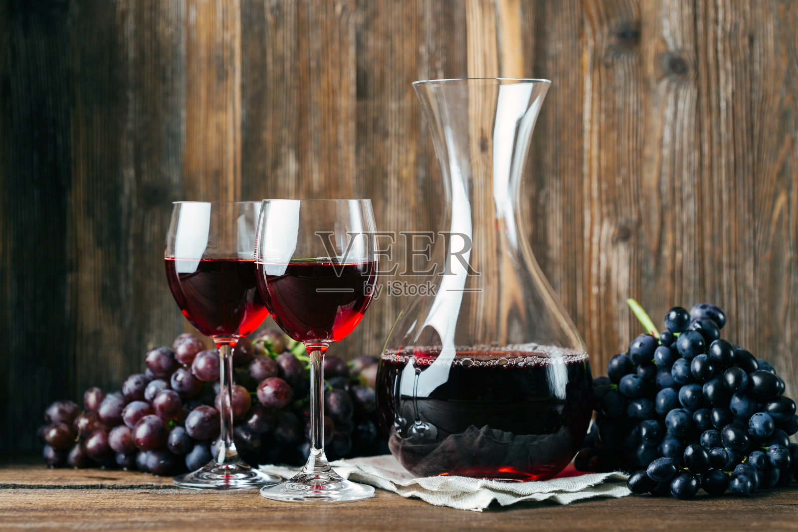 醒酒器，红酒，两个玻璃杯和一串葡萄在木背景上照片摄影图片