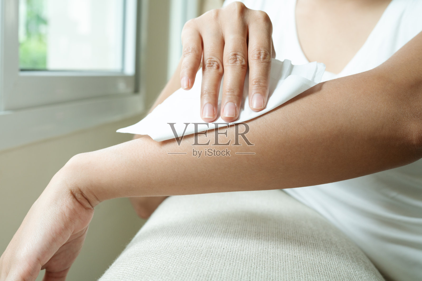 一个女人正在用白色的纸巾清洁她的手臂照片摄影图片
