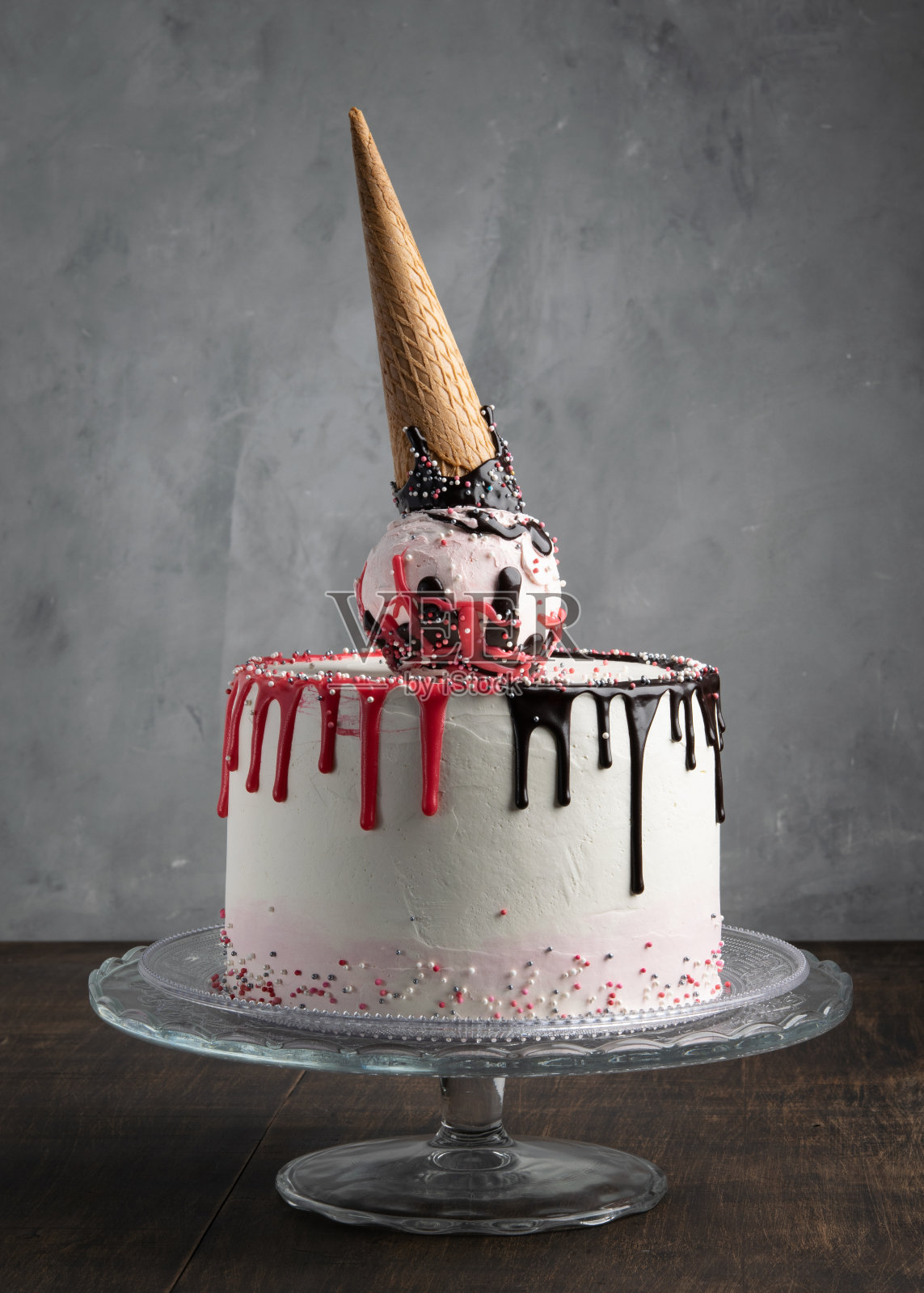 灰色背景上撒有糖屑的生日蛋筒蛋糕。做蛋糕装饰。副本的空间。庆祝活动的概念。时髦的蛋糕。垂直的。照片摄影图片