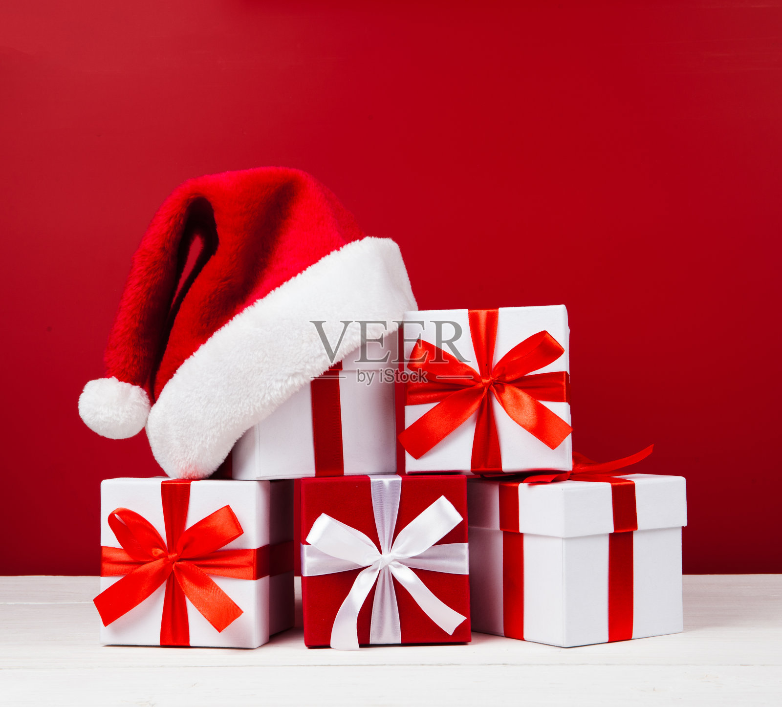 红色和白色的圣诞礼物盒的形状为金字塔和圣诞老人的帽子在顶部的红色背景照片摄影图片