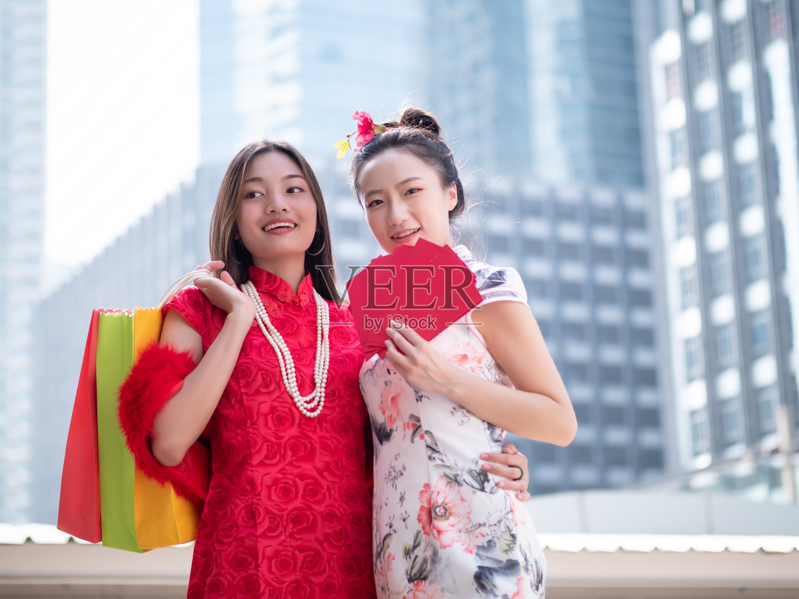 在泰国曼谷市中心，年轻的亚洲女人穿着中国服装，拿着购物袋和红包。中国新年与购物概念照片摄影图片