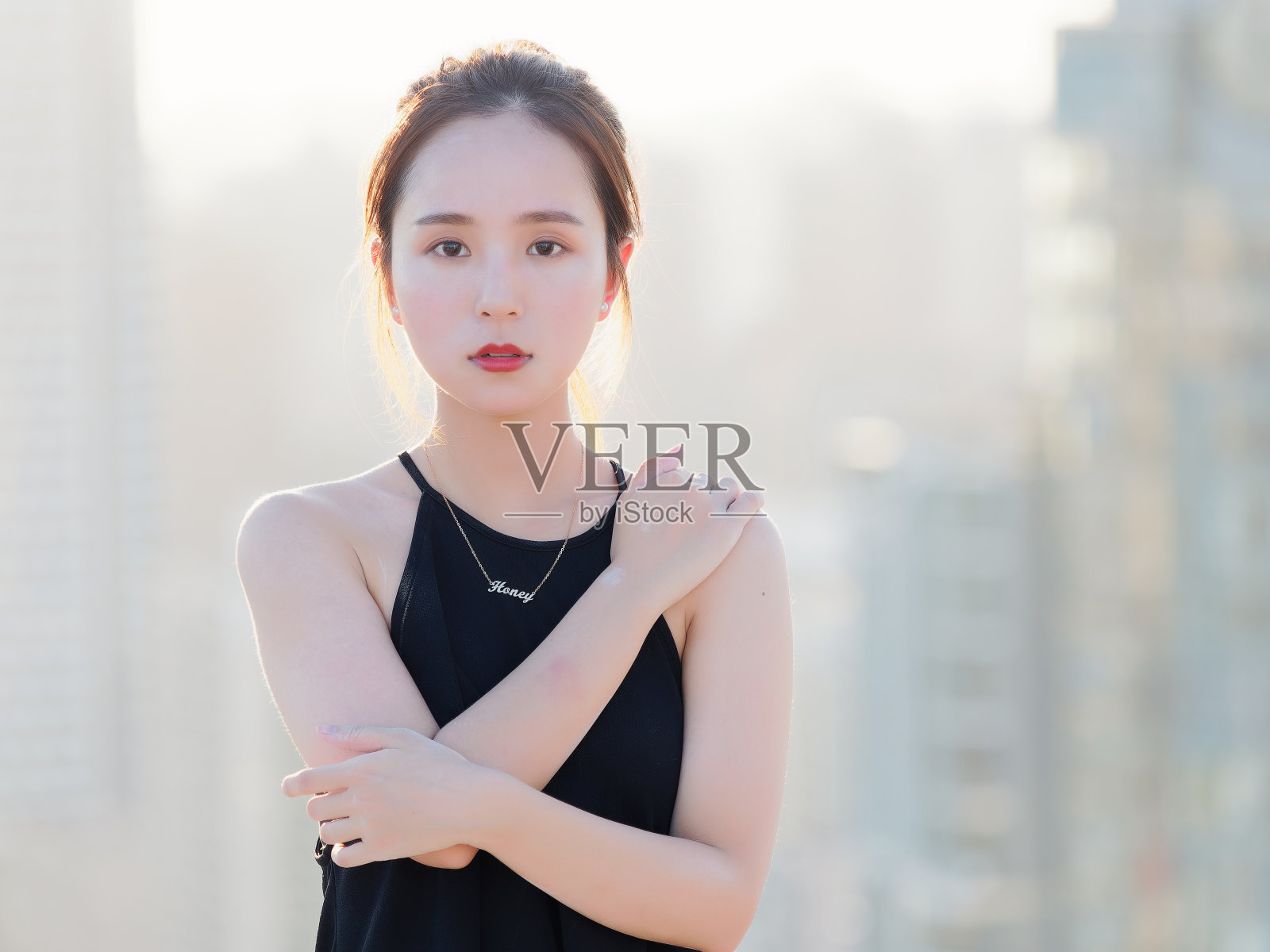 美丽的中国年轻女孩穿着性感的黑色连衣裙与肩在夏天的城市与背光和黄昏的城市背景。户外时尚写真魅力性感时尚淑女。照片摄影图片