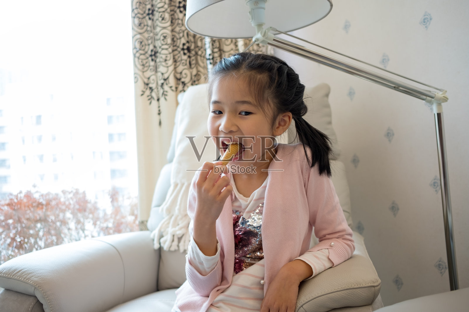 亚洲小女孩很喜欢在家吃零食照片摄影图片