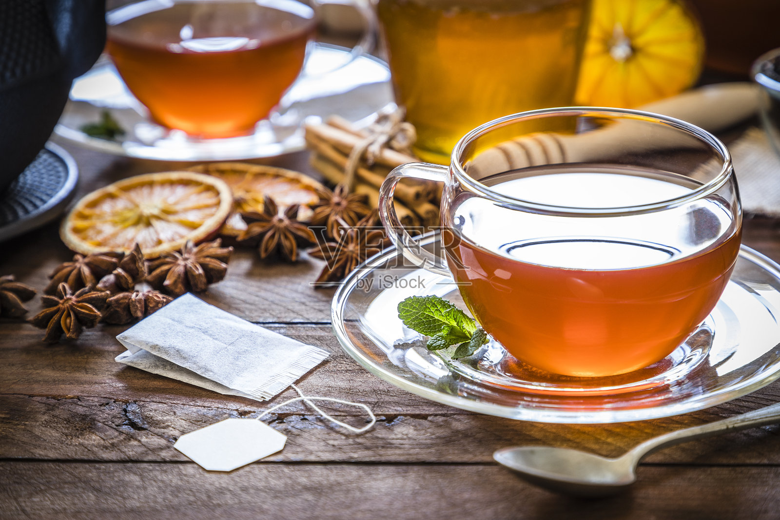 喝茶时间:一杯茶，肉桂棒，八角，橘子干放在木桌上照片摄影图片