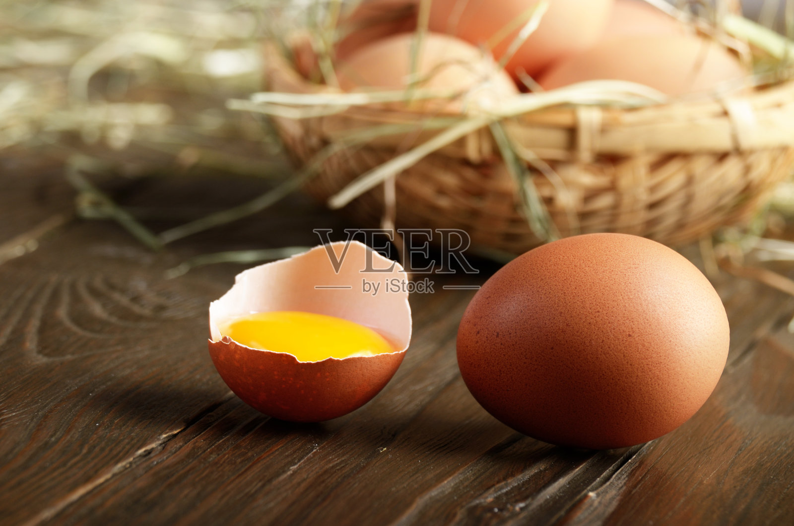 带蛋黄的破鸡蛋和新鲜的棕色有机鸡蛋放在木桌上照片摄影图片