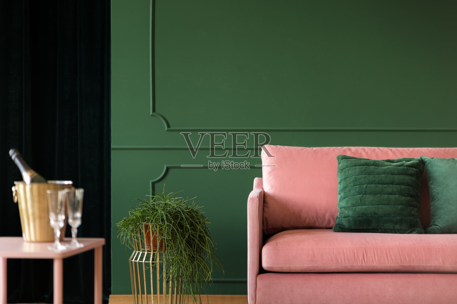 在深绿色的客厅内部，花朵旁边的粉红色沙发和祖母绿的枕头，复制空间在空的墙壁上照片摄影图片