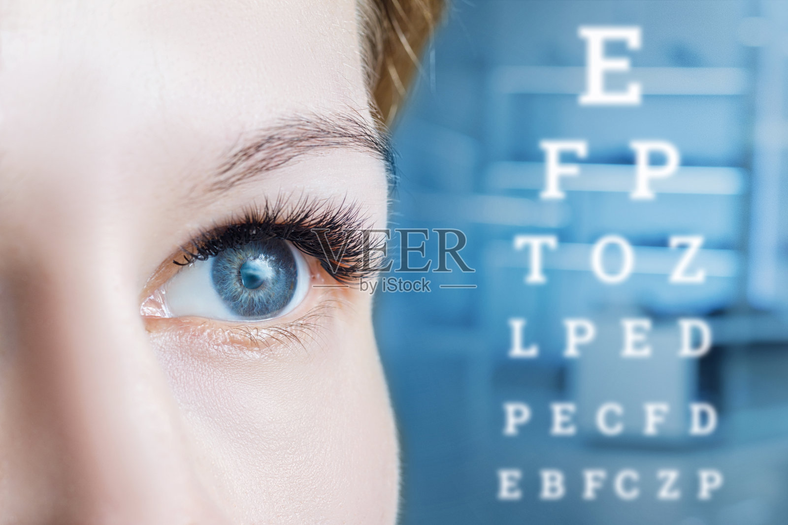 一个女性眼睛的特写和一个视力测试表。照片摄影图片