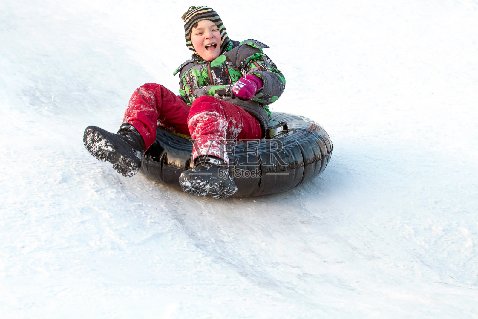 快乐的男孩和雪管。冬天的乐趣。用雪道从山上滑下来照片摄影图片