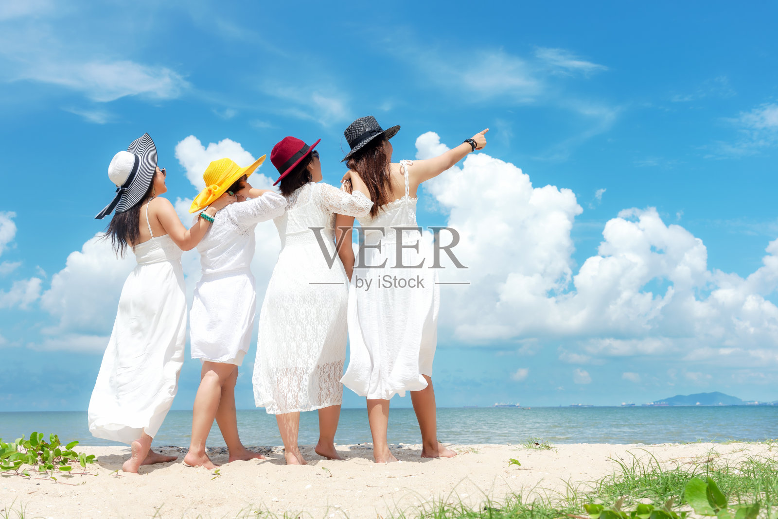 集团家庭亚洲妇女穿着时尚的白色连衣裙站在沙滩上，户外阳光的背景。照片摄影图片