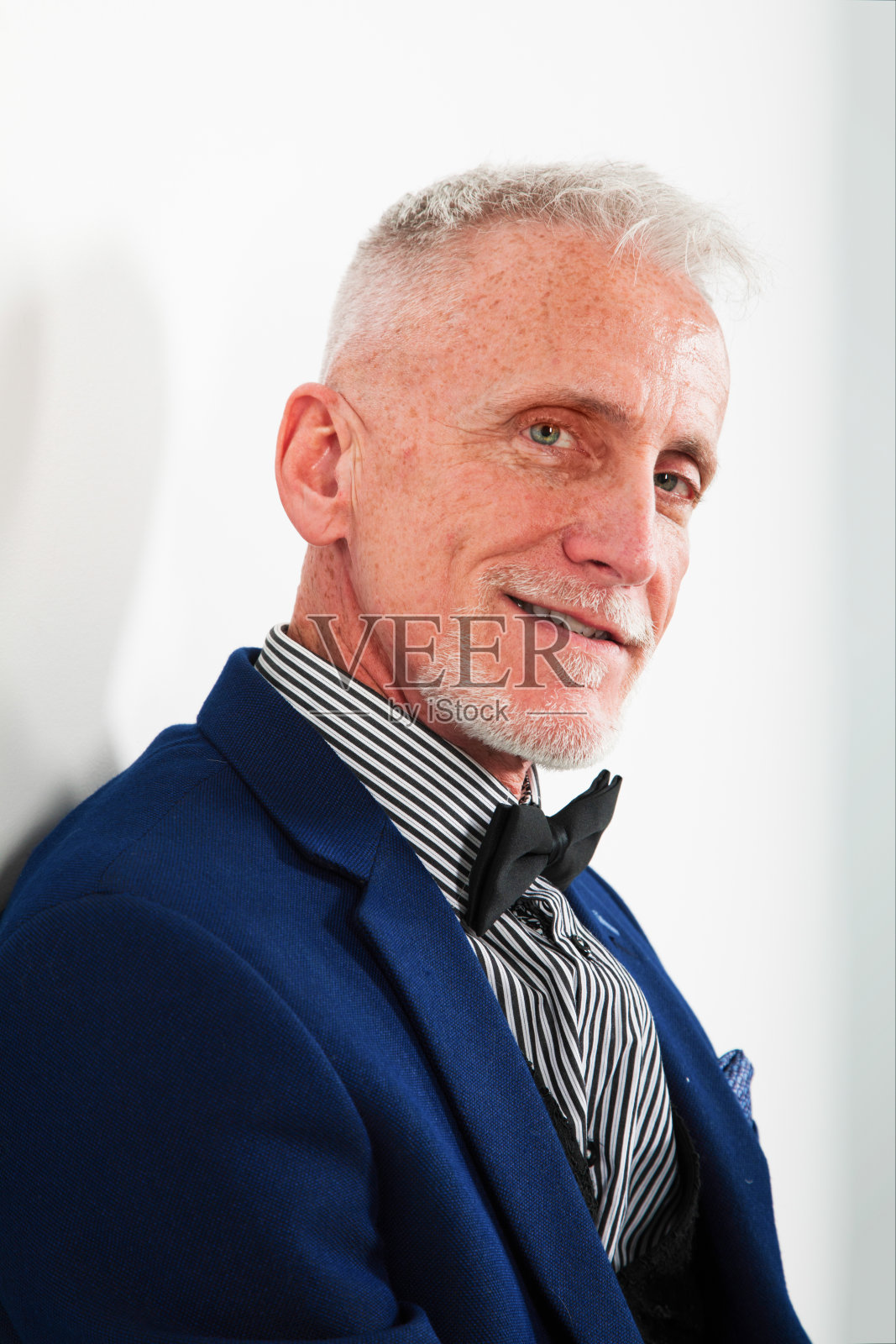 成熟的男人微笑肖像在灰色背景的蓝色西装背光照片摄影图片