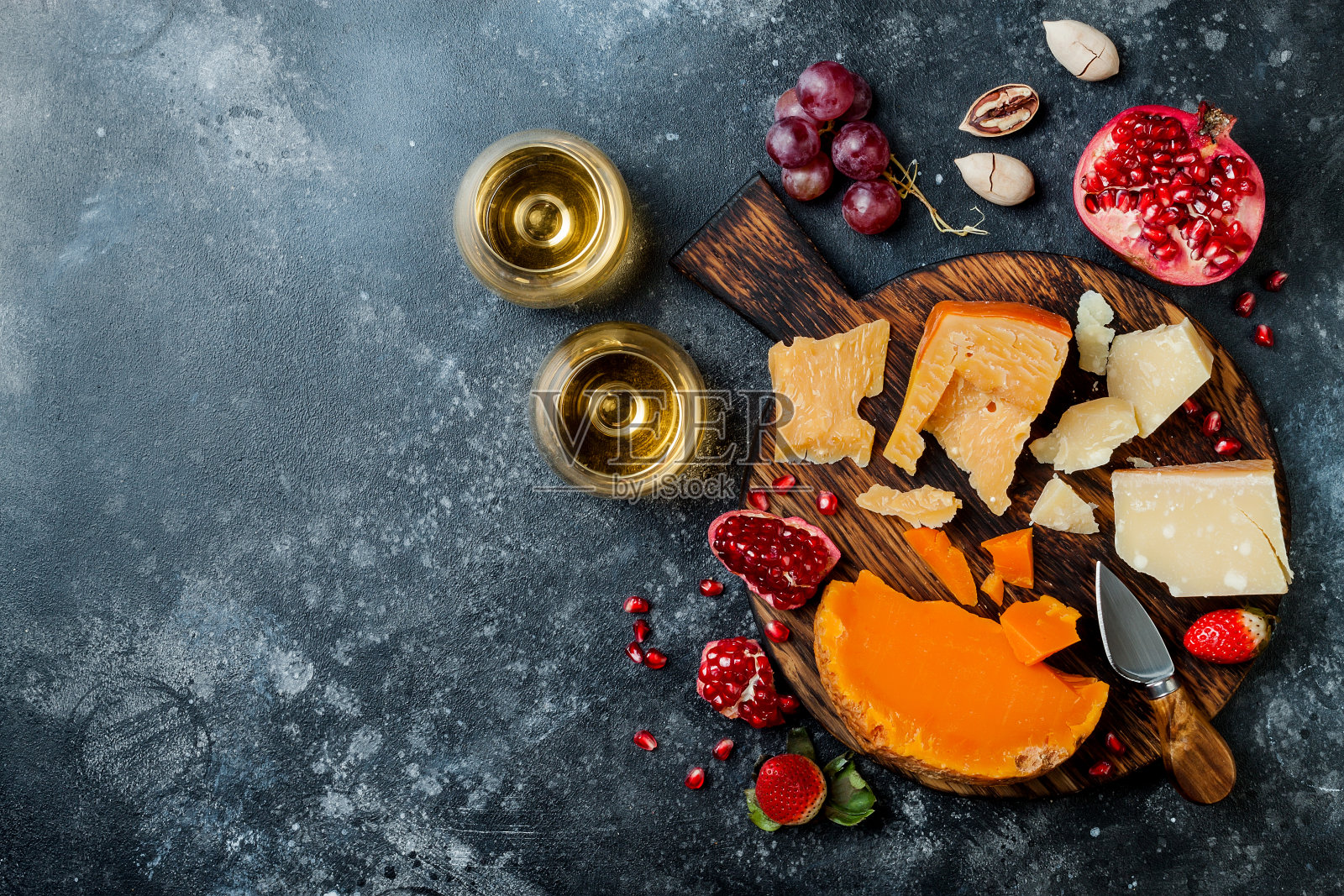 各种奶酪板或拼盘，搭配各种奶酪，葡萄，蜂蜜，坚果和葡萄酒。黑石的背景。俯视图，平放照片摄影图片