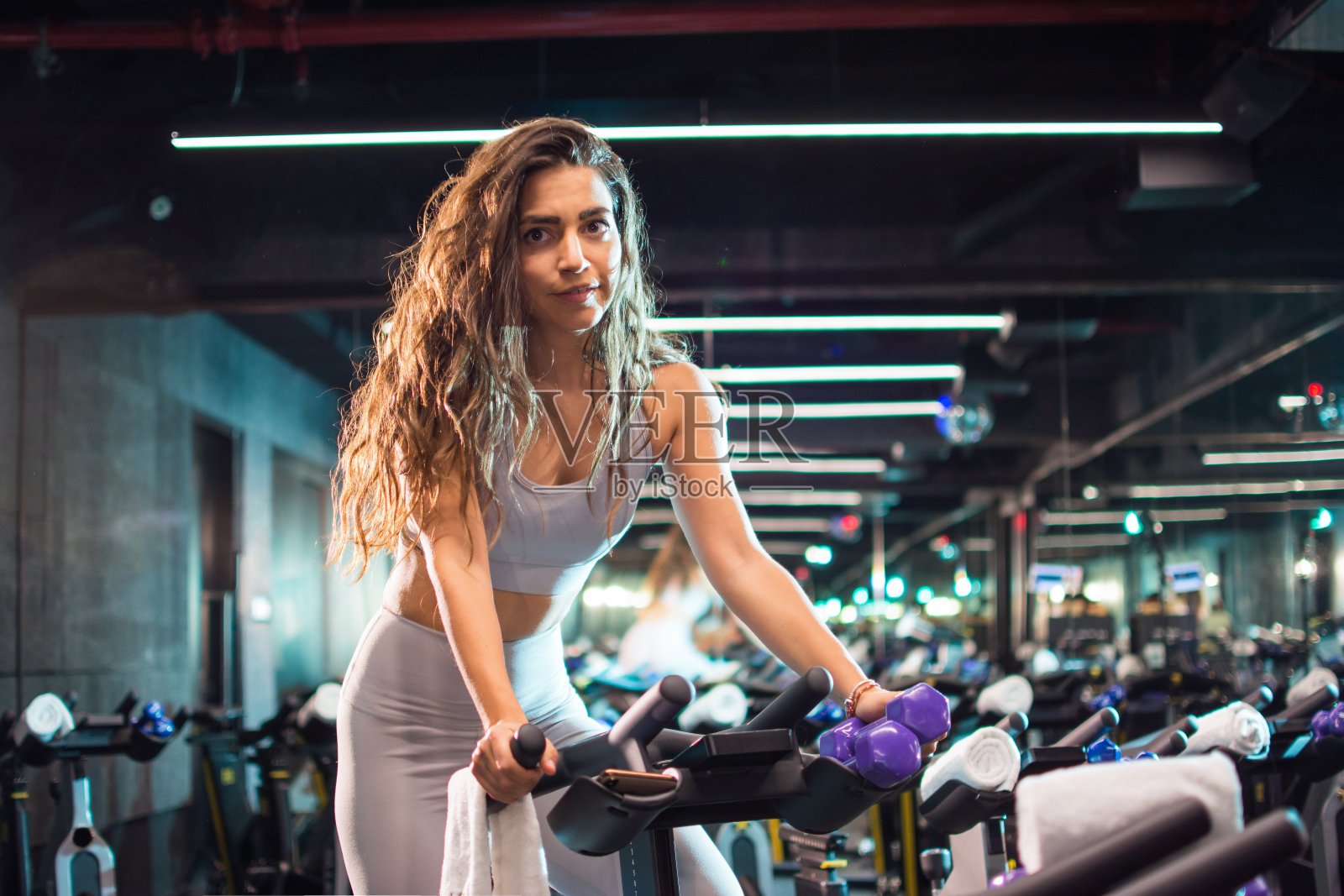 美丽的年轻女子在自行车机上锻炼在健身房照片摄影图片