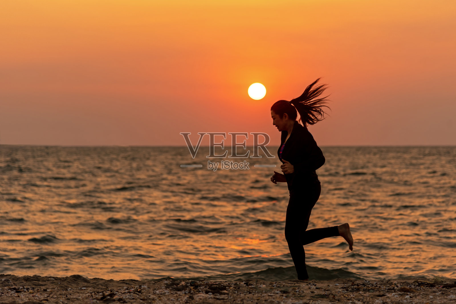 剪影跑步者的脚跑在海滩上在日落室外。亚洲健身和运动女人为健康和放松跑步。体育的概念照片摄影图片