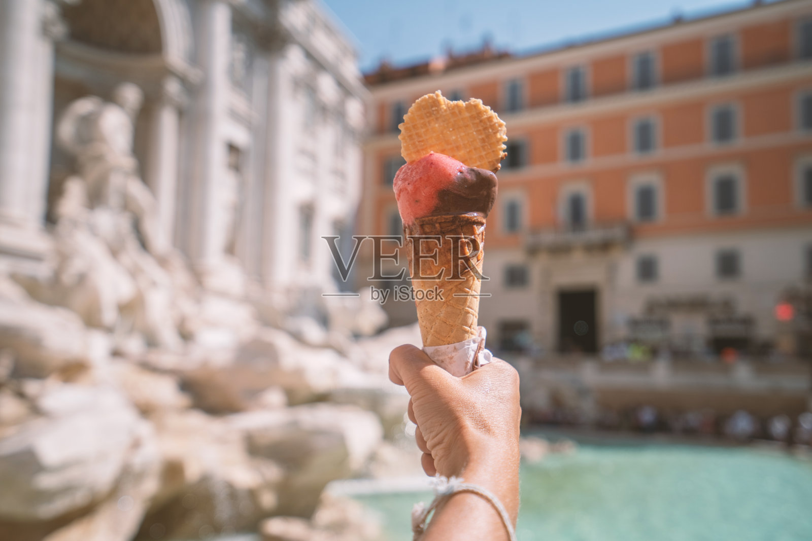意大利罗马的特莱维喷泉上，一只手拿着意大利冰淇淋照片摄影图片