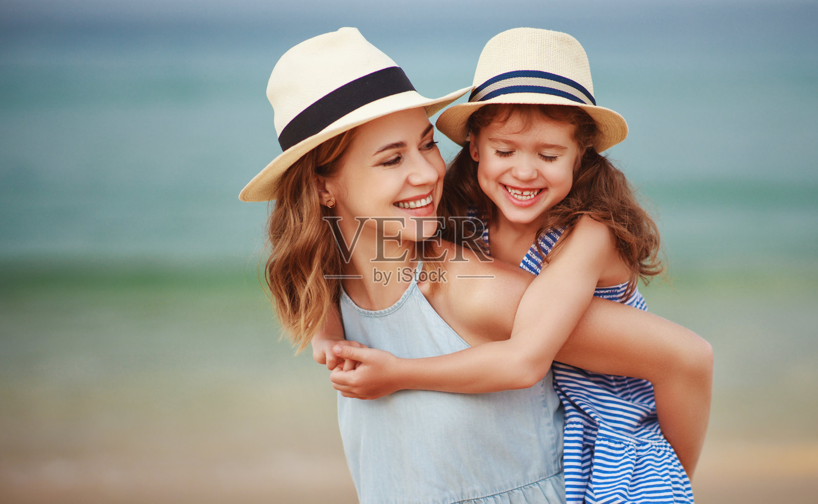 幸福的家庭在海滩。母亲和女儿在海上拥抱照片摄影图片