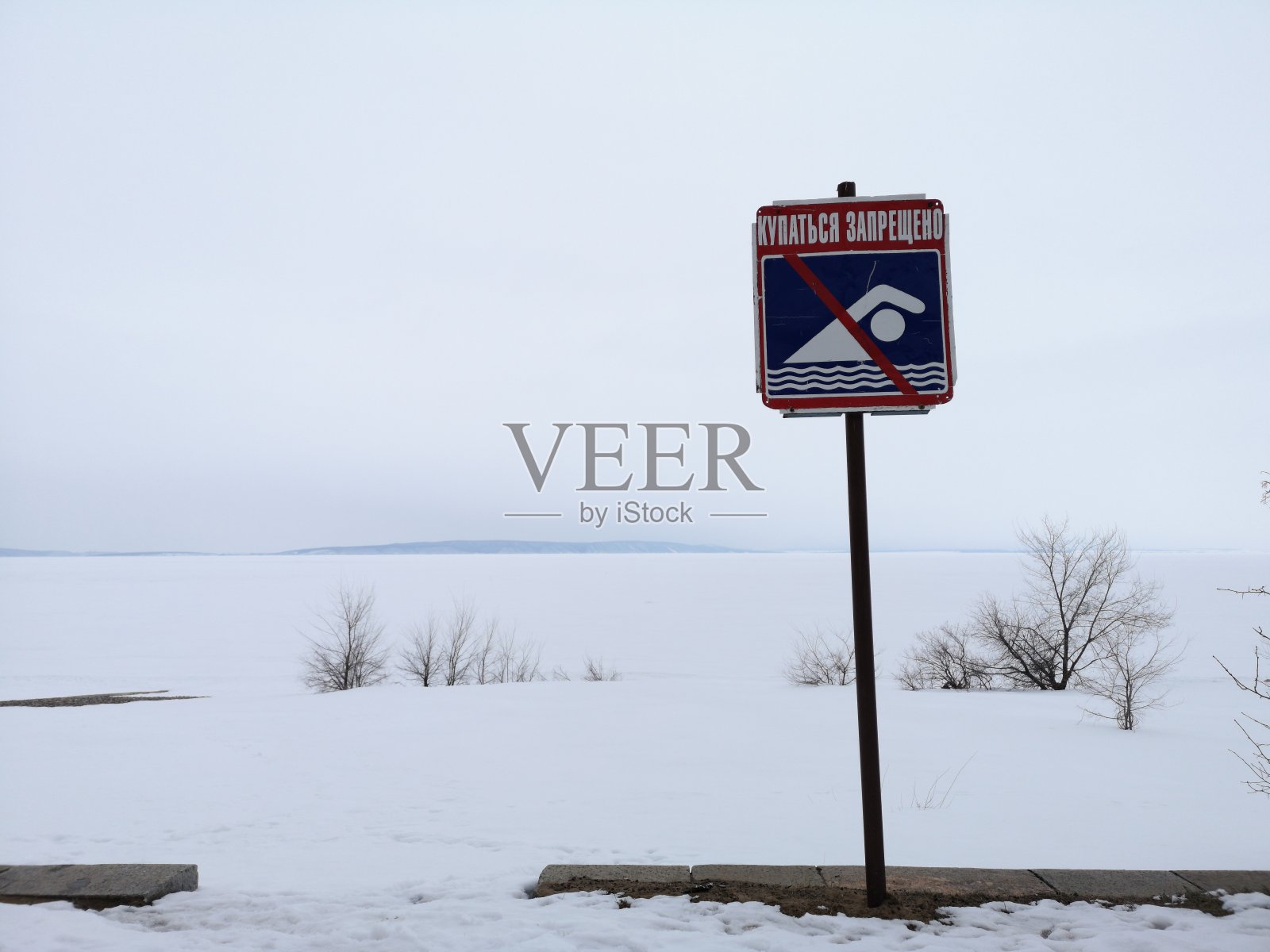 禁止在雪地里游泳的标志，背景是冬季冰冻的俄罗斯湖照片摄影图片