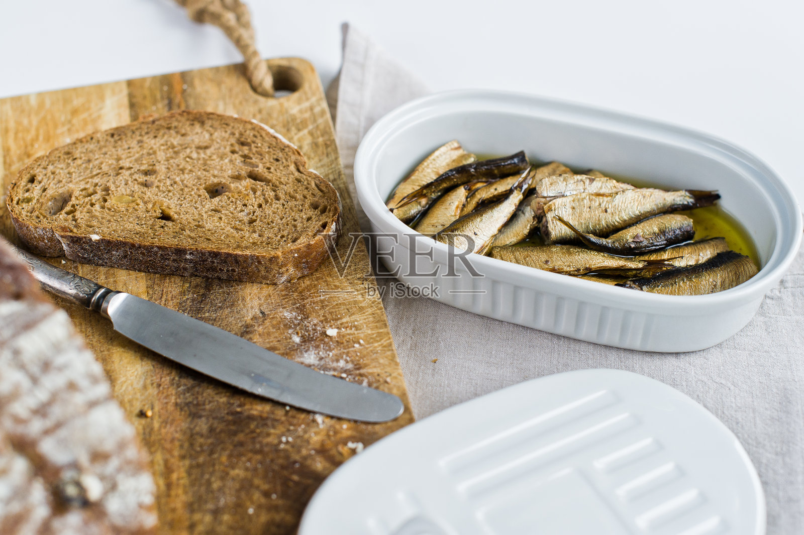 烤鱼三明治，陶瓷罐，木切板和黑面包。白色背景，俯视图。照片摄影图片