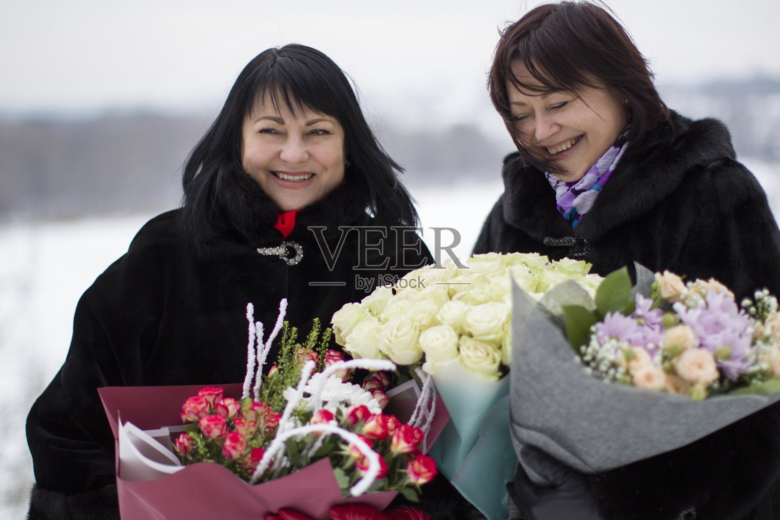 两个成熟的美女捧着花束。老朋友。女人的友谊。照片摄影图片