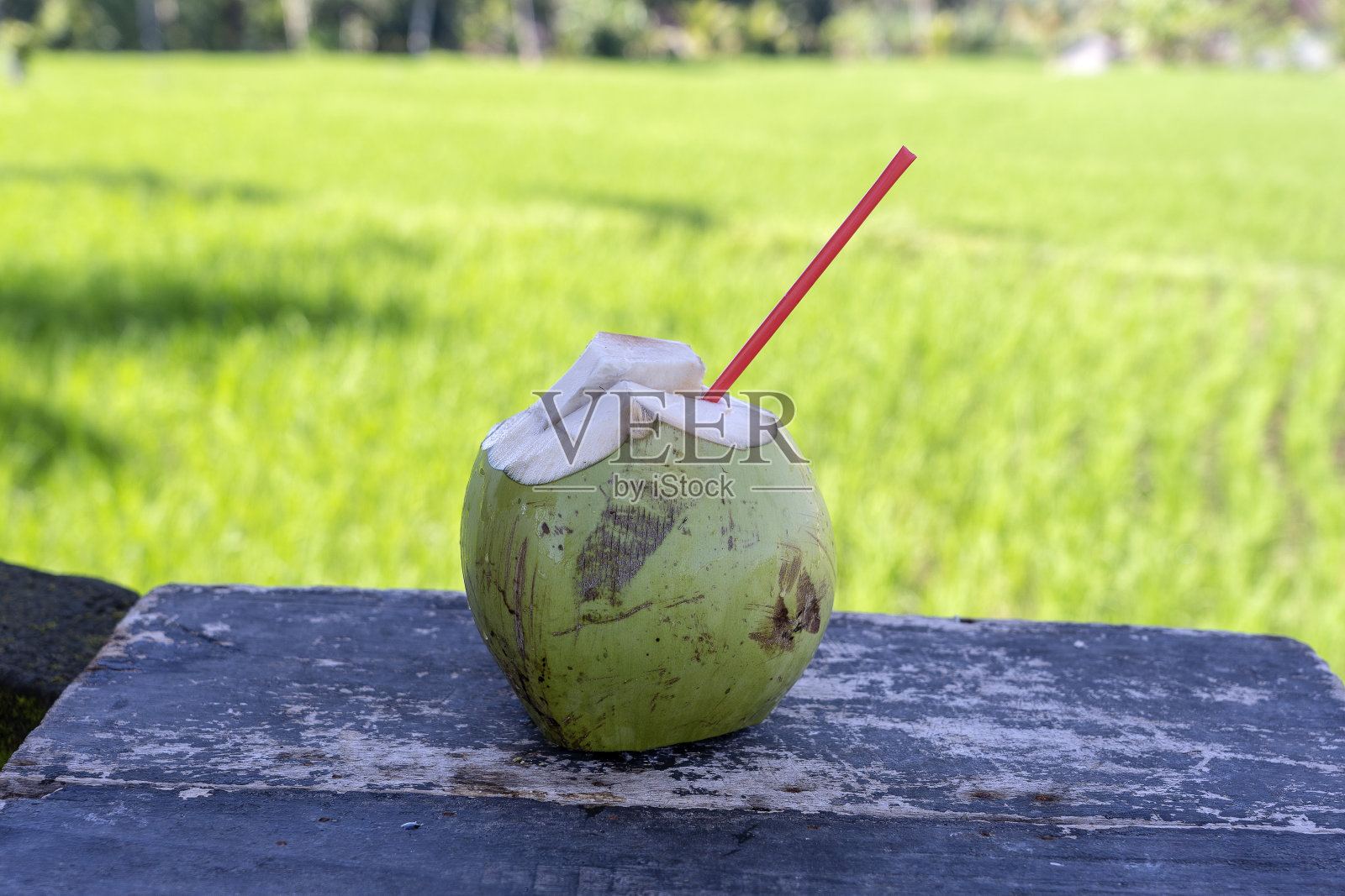 甜的绿色椰子水和饮用稻草在木板上。椰子热带水果在巴厘岛附近的水稻梯田，印度尼西亚。特写镜头照片摄影图片