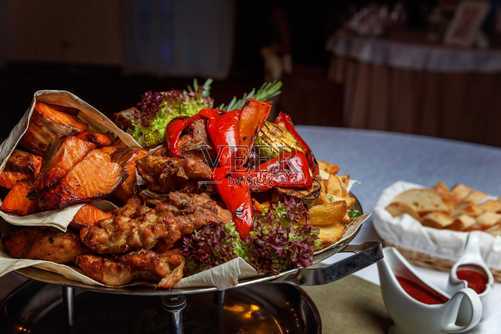 什锦烤肉、炒蔬菜、烤鲑鱼片装饰于热菜中照片摄影图片