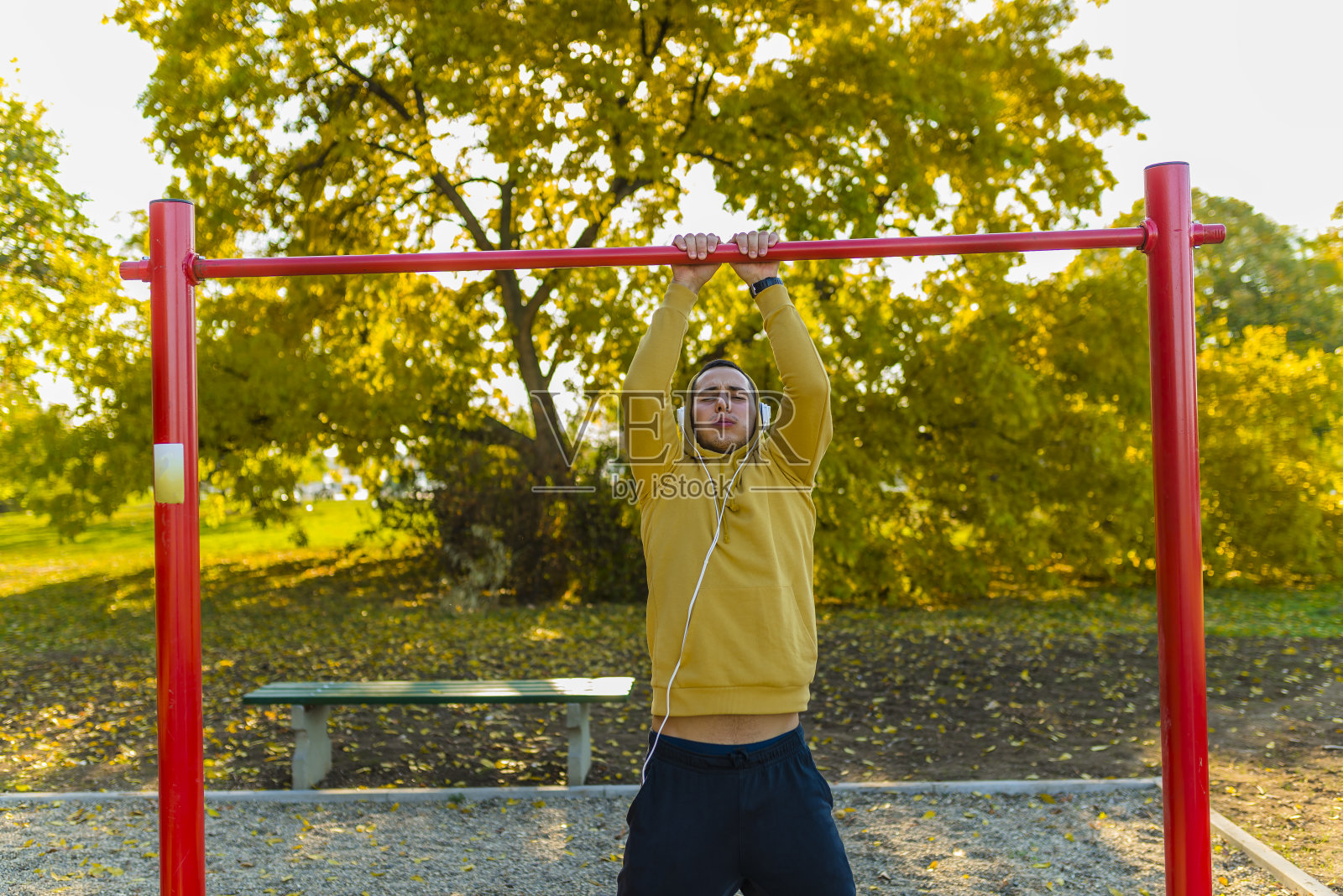 年轻肌肉男运动员在公园里做引体向上运动照片摄影图片