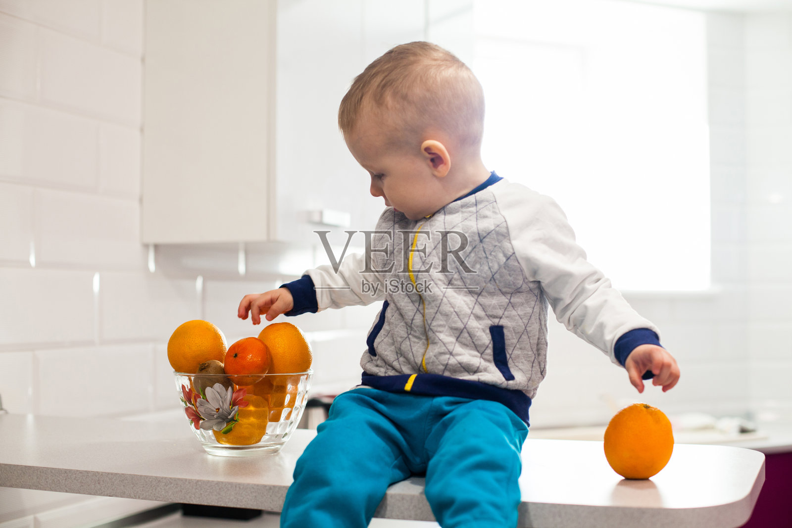 可爱的小孩在厨房里吃水果。儿童健康饮食理念照片摄影图片