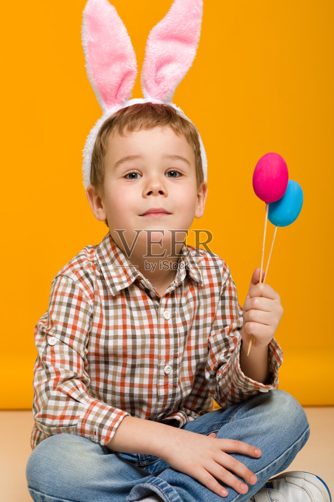 带着复活节兔子耳朵拿着彩蛋的小男孩照片摄影图片