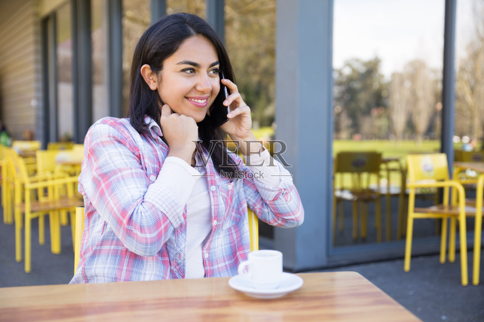 快乐的女士，一边打电话一边在街头咖啡馆喝咖啡照片摄影图片