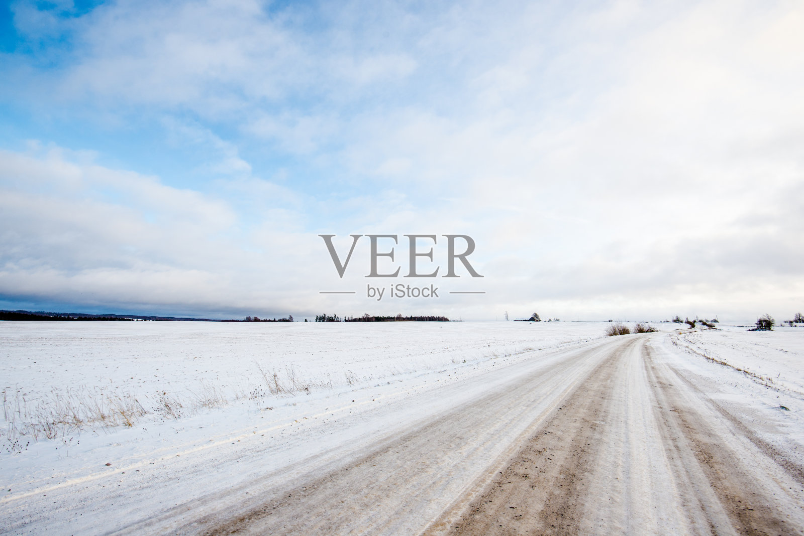 日落时分，一条穿过白雪覆盖的田野的路。阳光明媚的冬日照片摄影图片