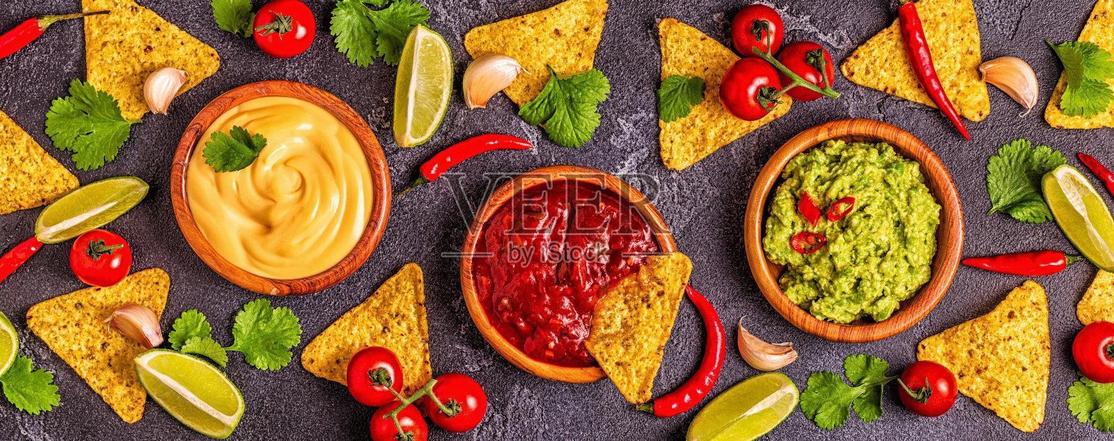 墨西哥食物背景:鳄梨色拉酱，莎莎酱，芝士酱和配料在黑色的背景照片摄影图片