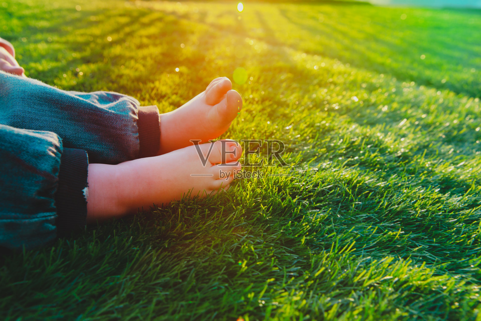 日落时分，小女孩光着脚踩在草地上照片摄影图片