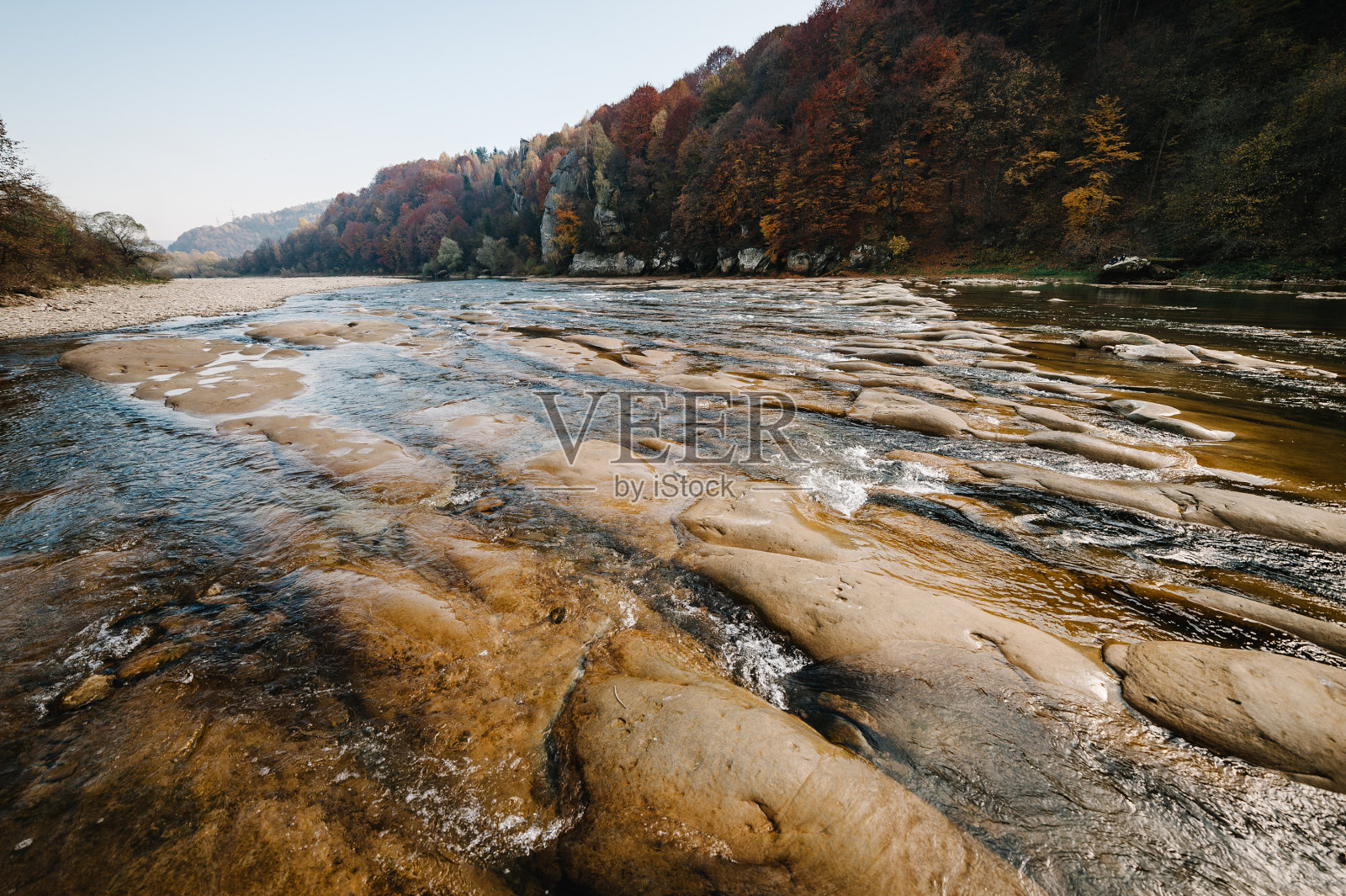 清澈的河流带着岩石通向山脉。
在日落。山上湍急的河水在岩石中流淌着蓝天。景观有森林，河流和石头。山的河。照片摄影图片