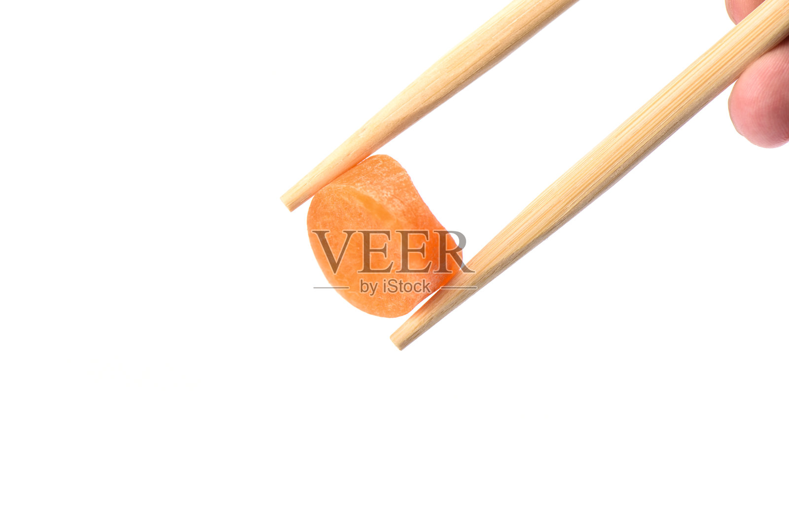 用筷子夹一圈成熟的胡萝卜，孤立地放在白色的背景上。照片摄影图片