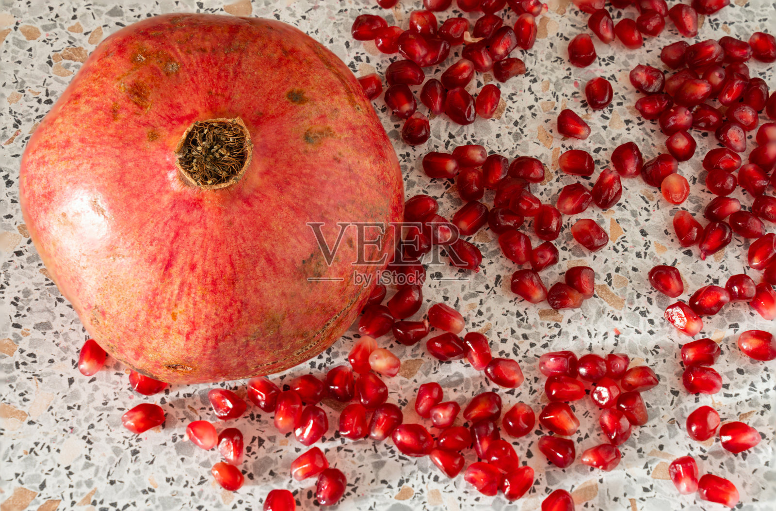 红色成熟的石榴籽在盘子上特写。大理石质地的桌子上放着石榴果实照片摄影图片