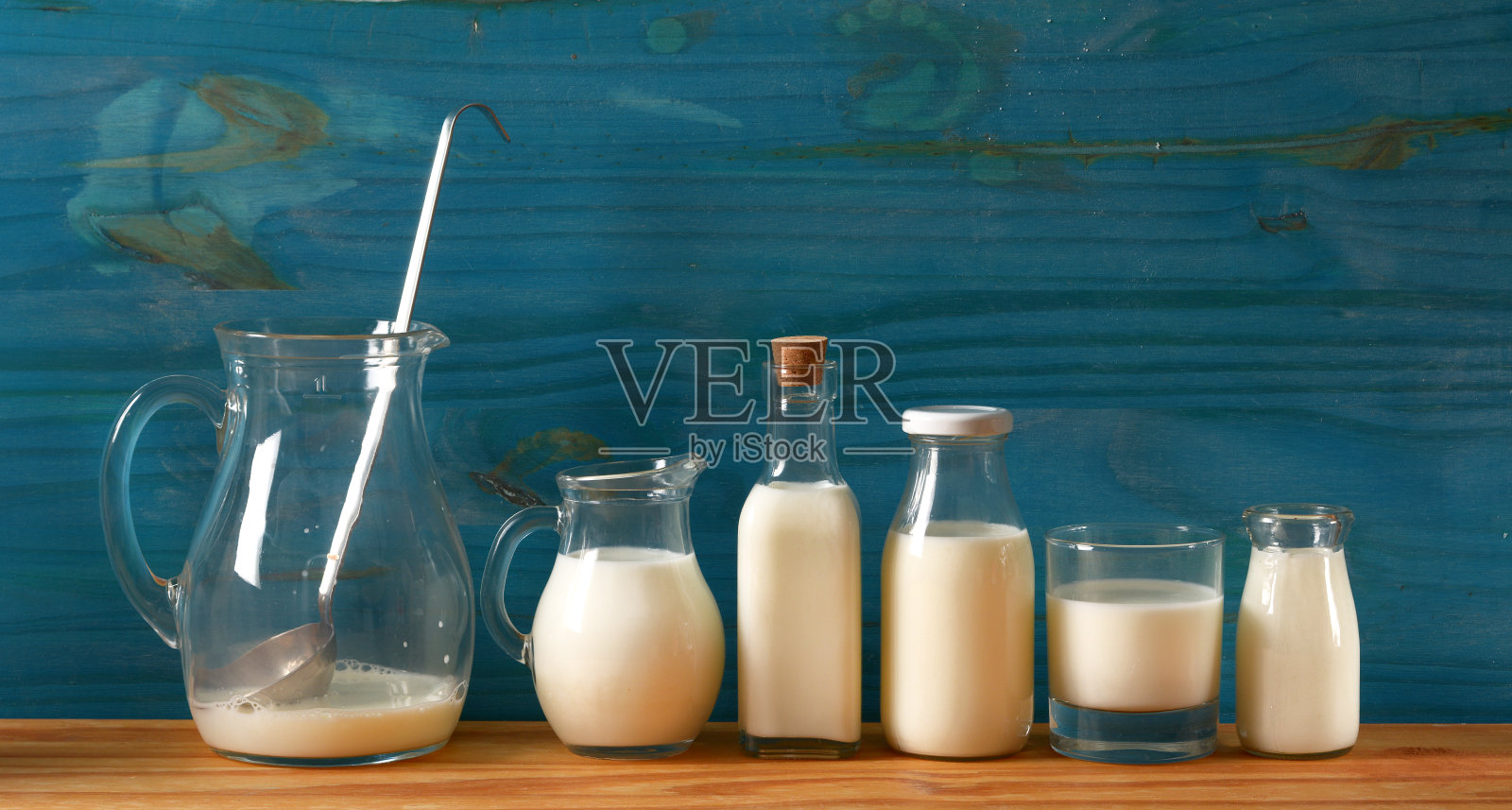 新鲜牛奶在玻璃容器与蓝色木制背景-特写照片摄影图片