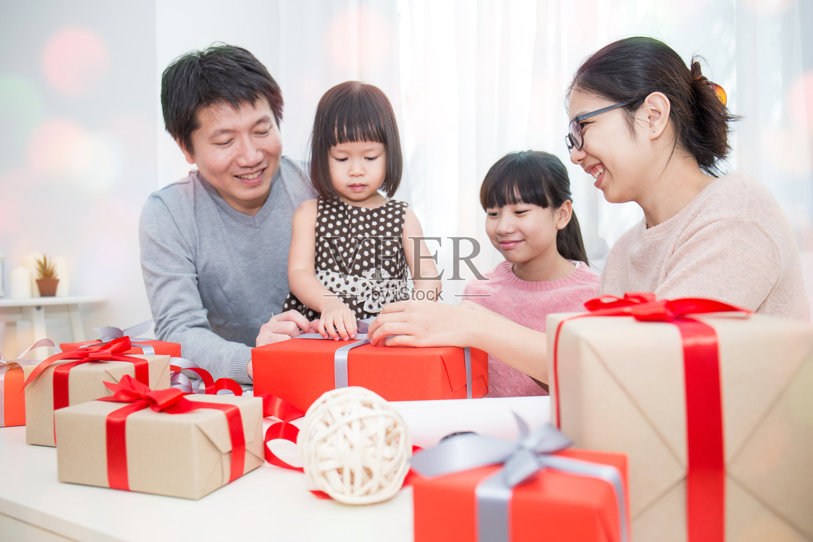 亚洲家庭在沙发上赠送圣诞礼物，亚洲家庭庆祝圣诞节节礼日打开礼物照片摄影图片