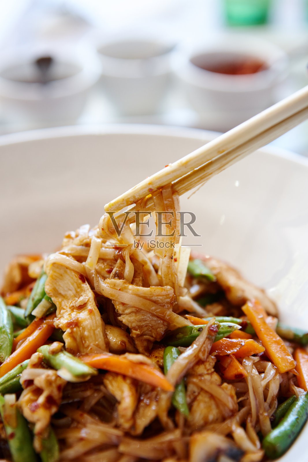筷子从一碗炒鸡中夹起食物照片摄影图片