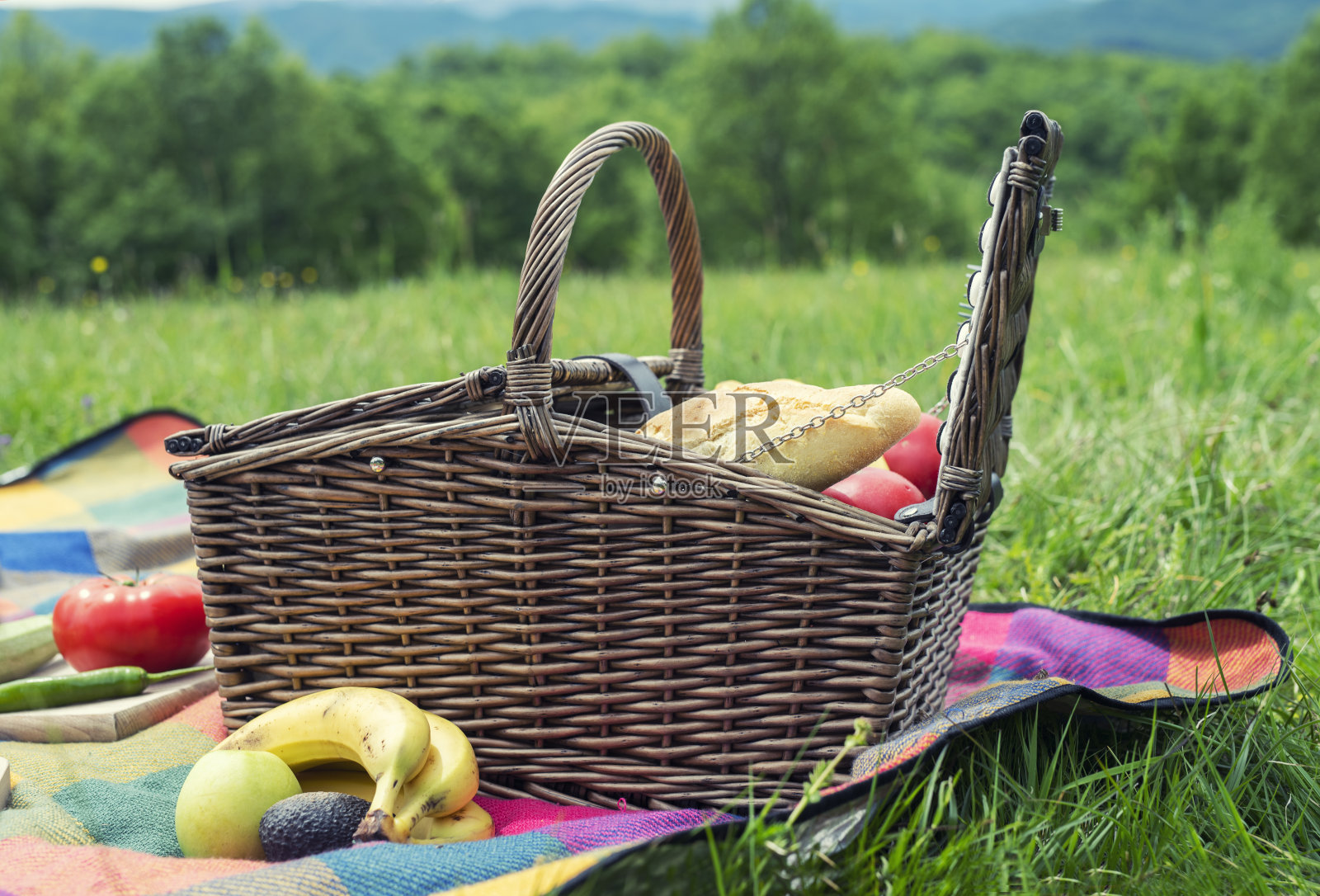 野餐毯子上放着食物的篮子。照片摄影图片