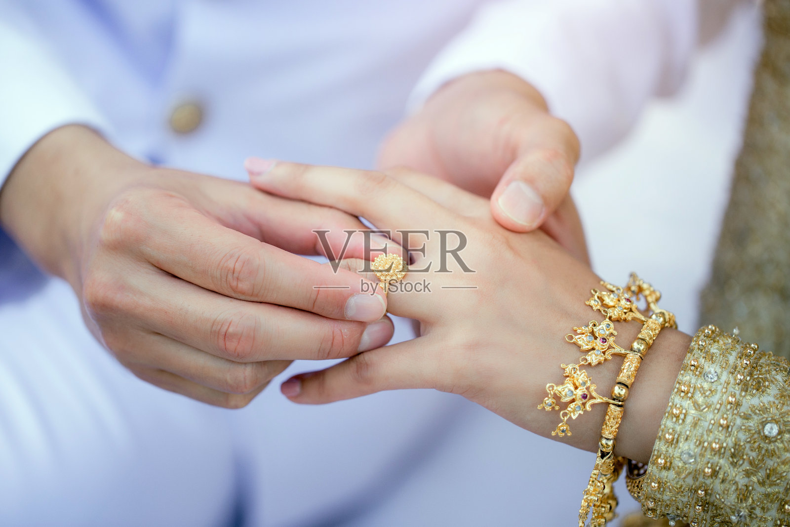 新郎把结婚戒指戴在新娘的手指上。照片摄影图片