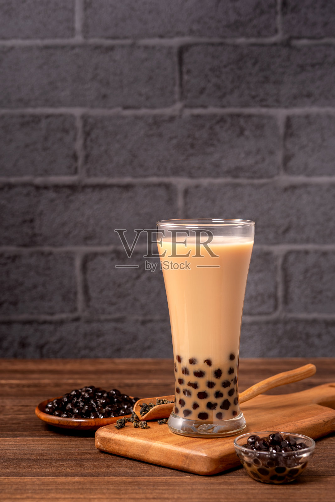 美味的珍珠奶茶和珍珠球在玻璃木桌和深灰色的砖背景，台湾流行的食品和饮料，近距离观看照片摄影图片