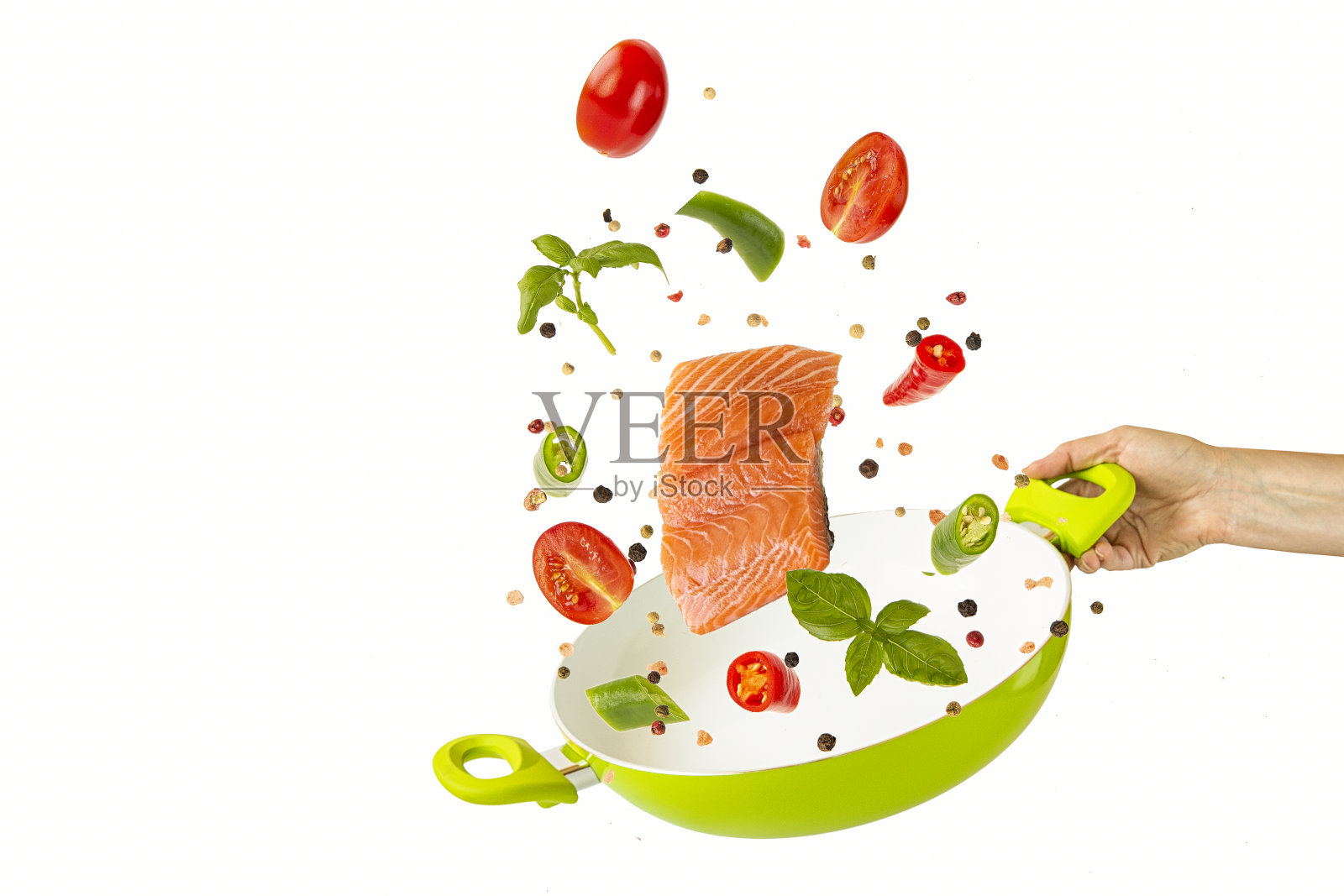 把鱼和蔬菜与香料放在一个绿色的平底锅里。孤立的项目在白色背景。飞行的食物照片摄影图片