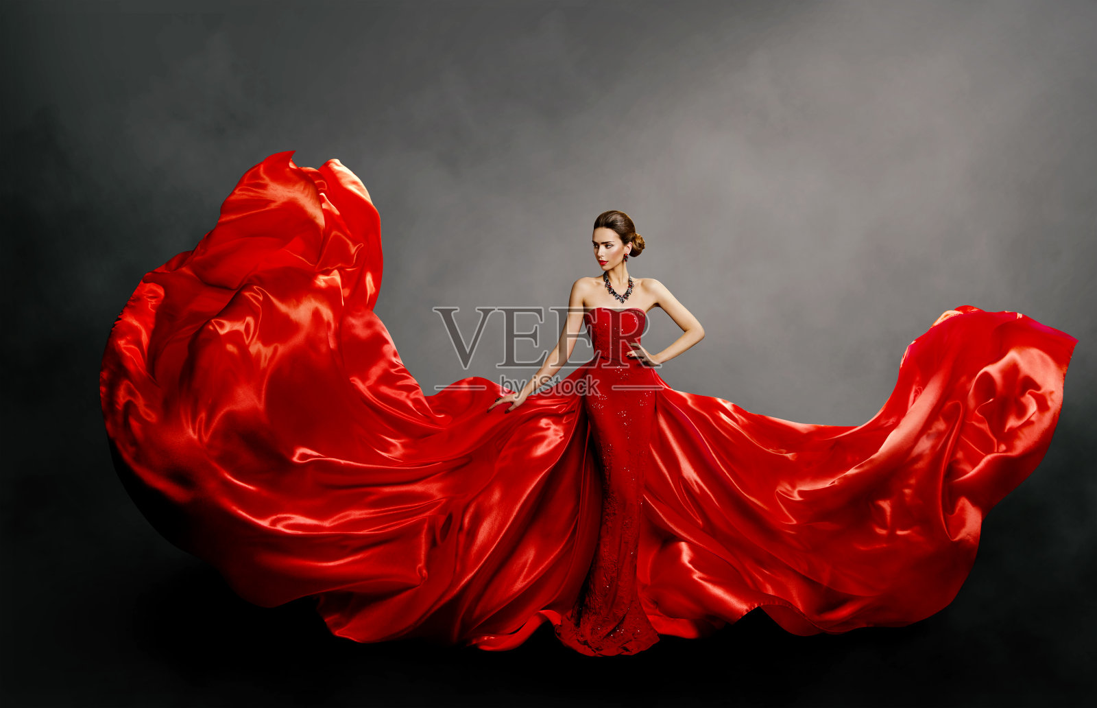 女人红裙，时尚模特长丝绸长袍在风中飘扬，飘动的面料照片摄影图片