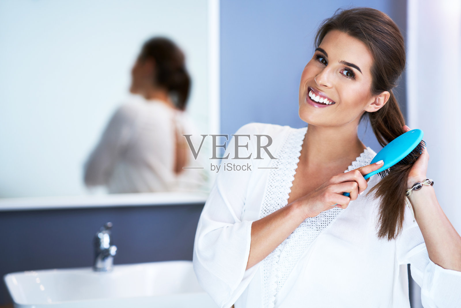 在浴室梳头的快乐女人照片摄影图片