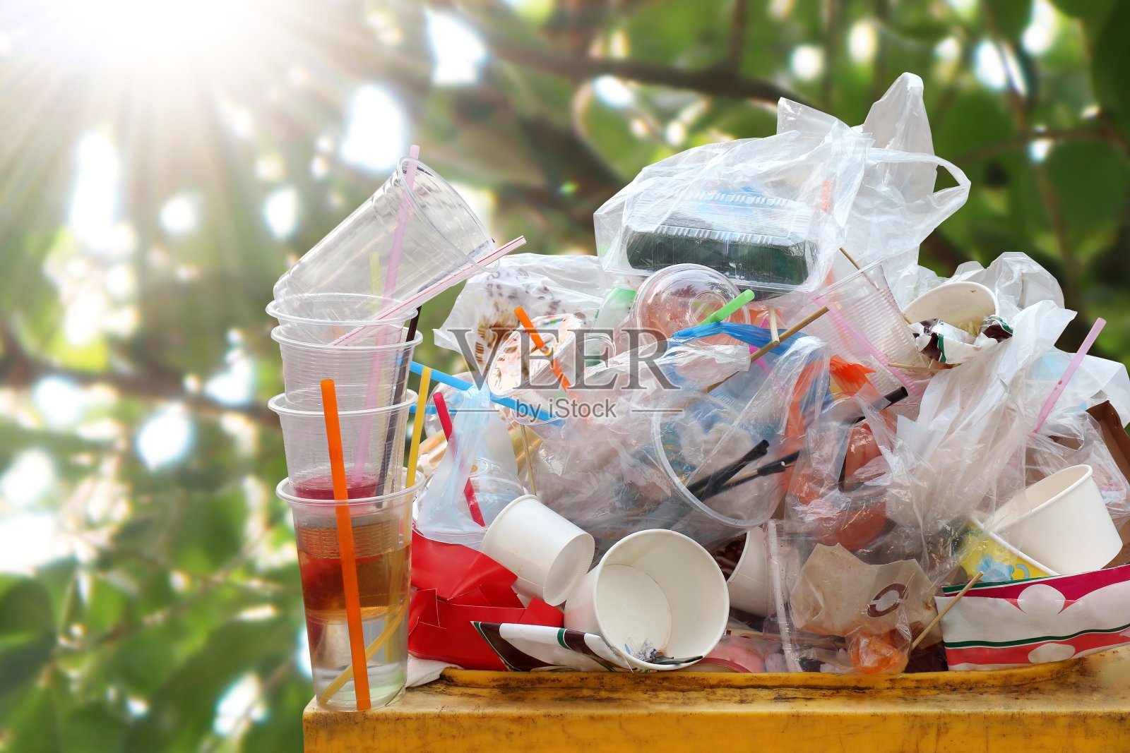 废塑料堆在垃圾桶，垃圾桶满垃圾桶垃圾，塑料袋垃圾大量的垃圾在自然树阳光的背景，垃圾许多特写照片摄影图片