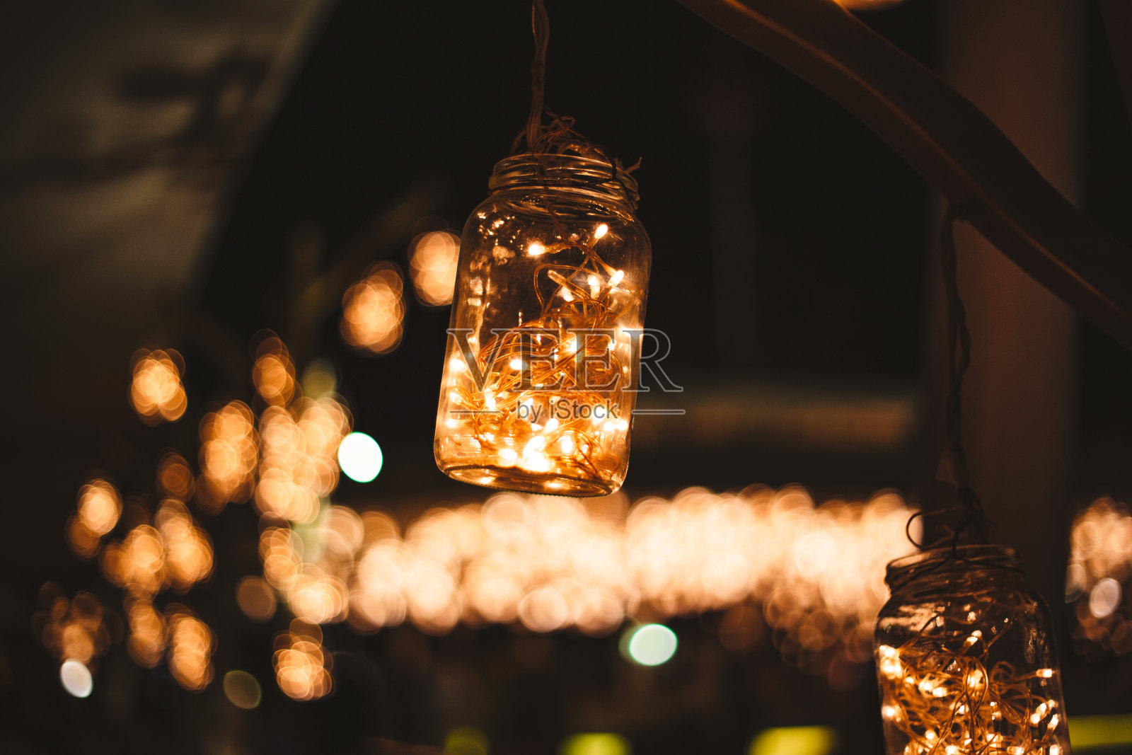 许多白炽灯泡挂在椰子树之间，为海滩派对。复古灯装饰是准备在海边举行的婚礼庆典。户外夜派对概念。照片摄影图片