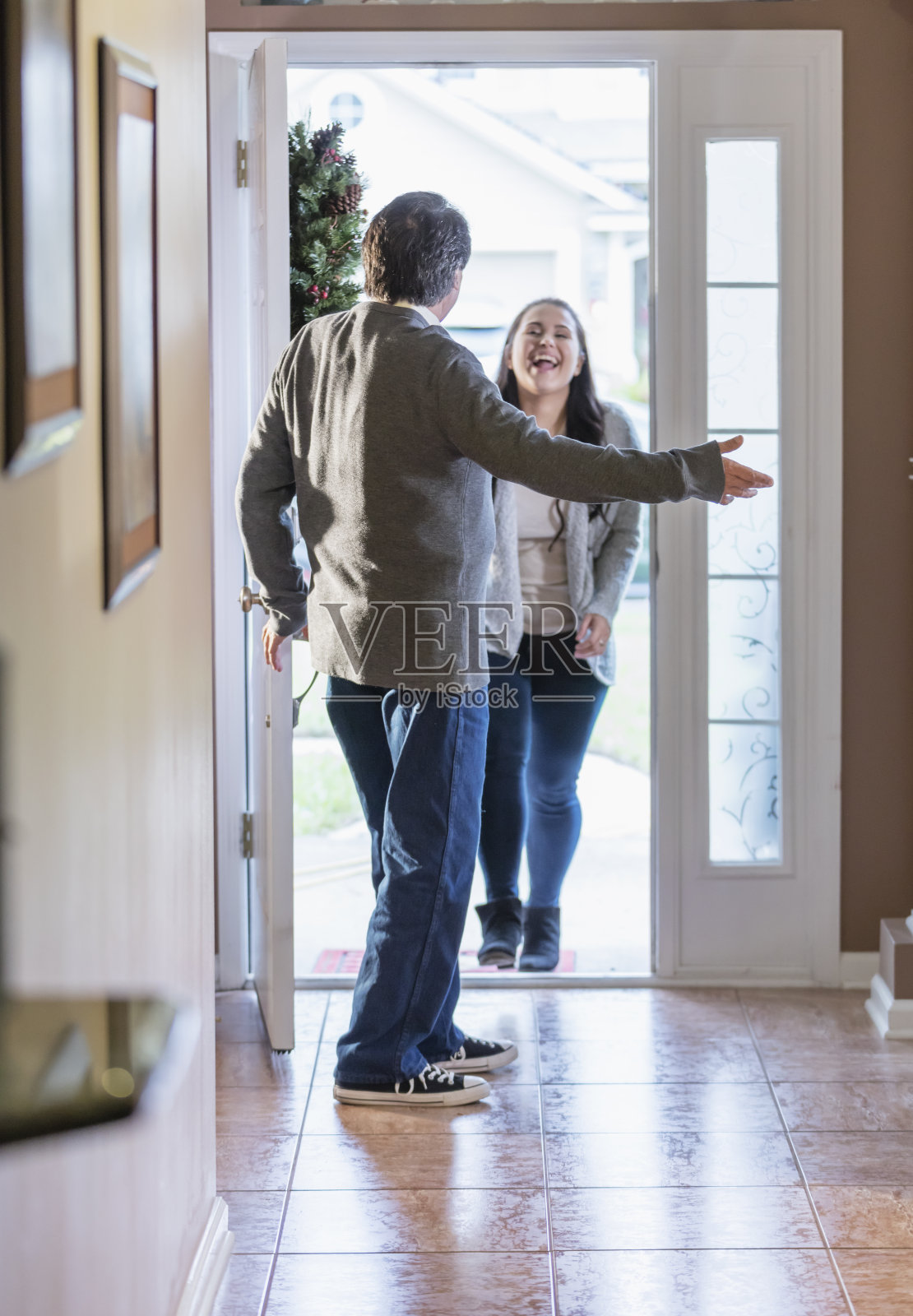 西班牙裔老人打开前门，迎接客人照片摄影图片