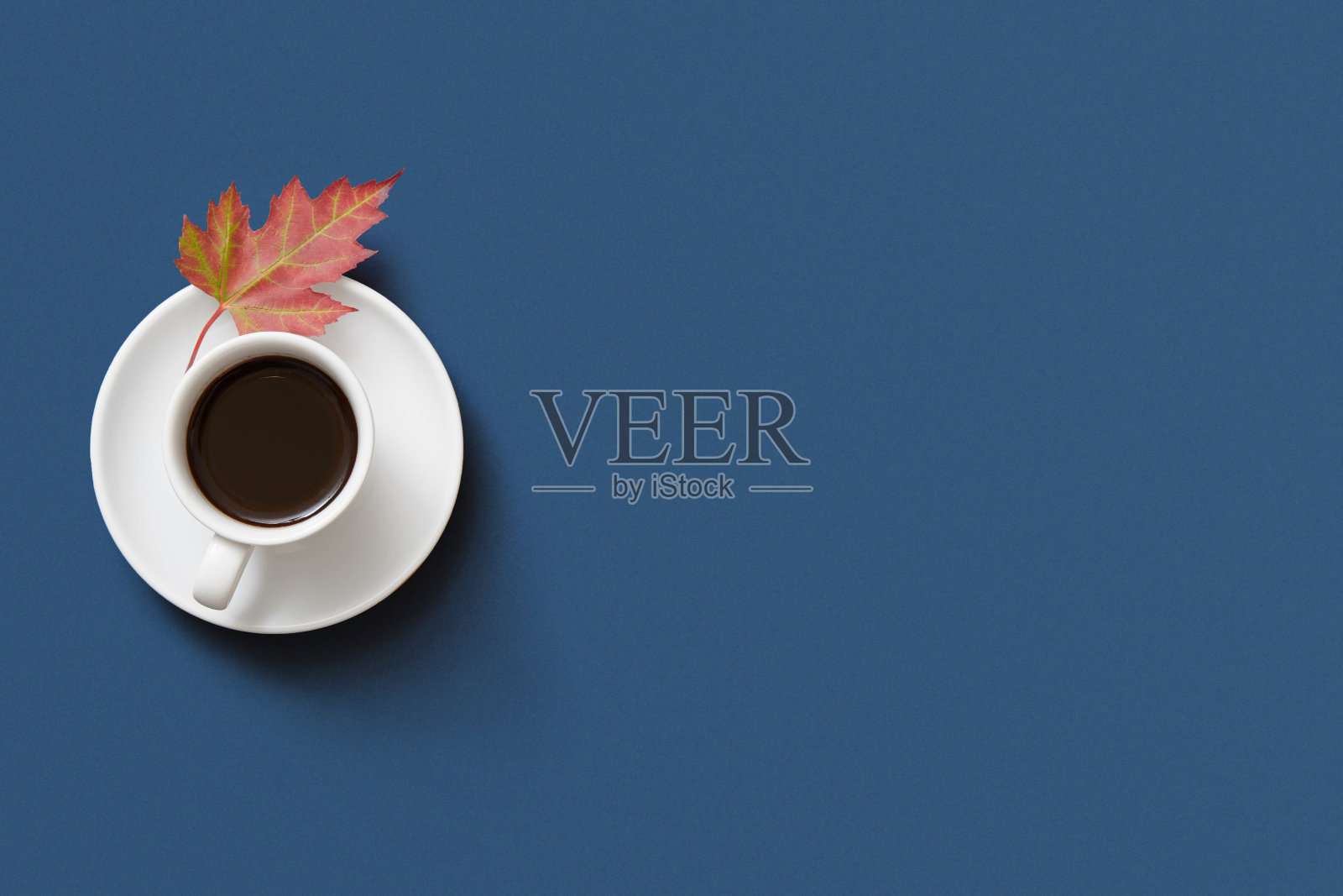 秋天的咖啡杯在蓝色的背景与橙色的枫叶照片摄影图片