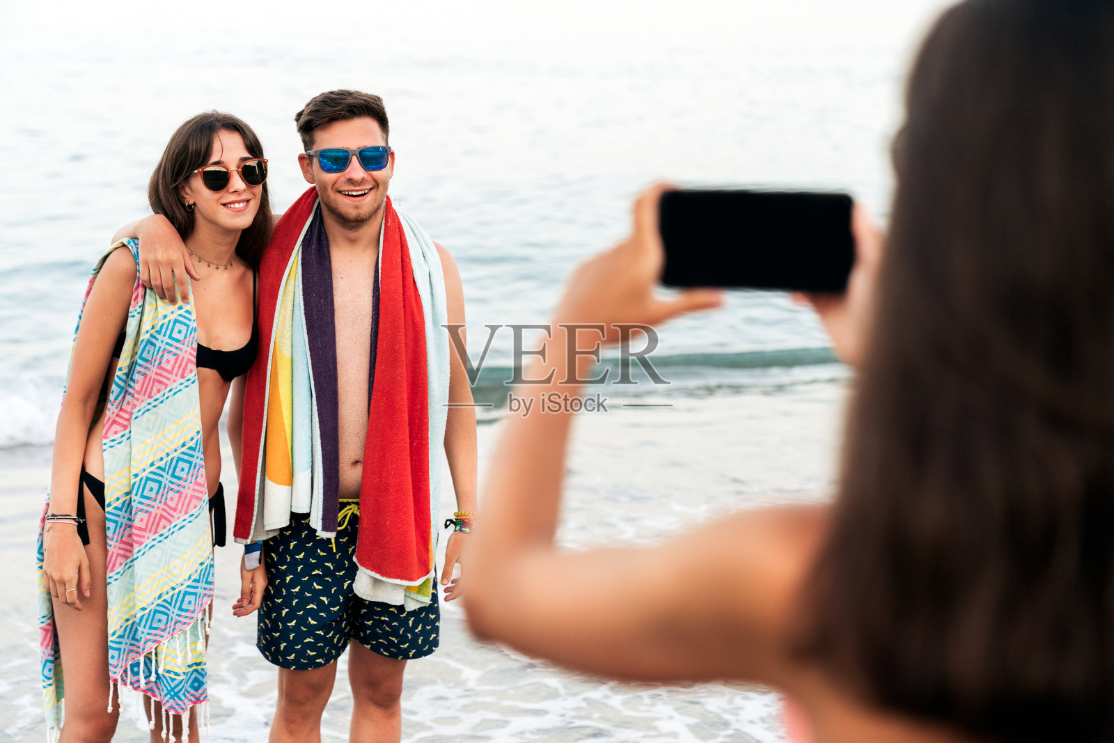 一名女子在海滩上游泳后给一对夫妇拍照照片摄影图片