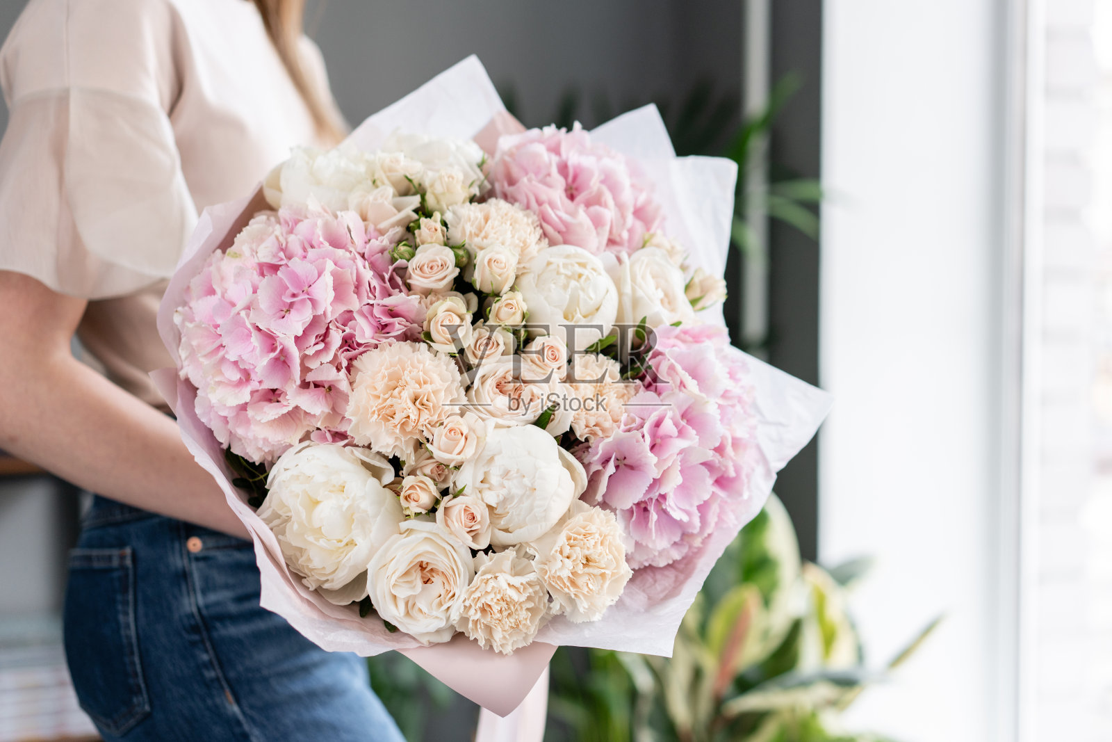 白色的牡丹和粉色的绣球花。女人手里拿着一束美丽的混合鲜花。花店概念。英俊的新鲜的花束。花交付。红色和粉红色。照片摄影图片